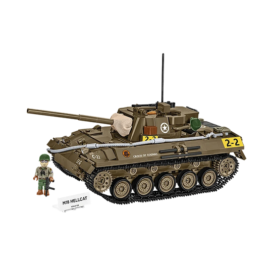 A photo of the model tank. It is made of various brown, grey and yellow pieces. It has its gun raised, and has functional tracks over its wheels. A model soldier stands next to it, behind a small plaque displaying the name of the tank.