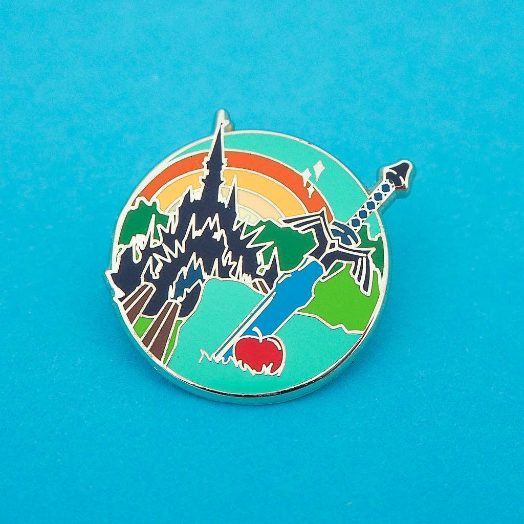 Colorful enamel pin with castle, sword, and apple design on a blue background