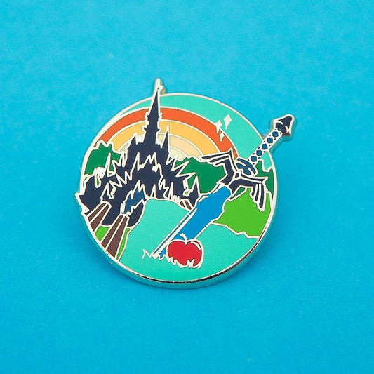 Colorful enamel pin with castle, sword, and apple design on a blue background