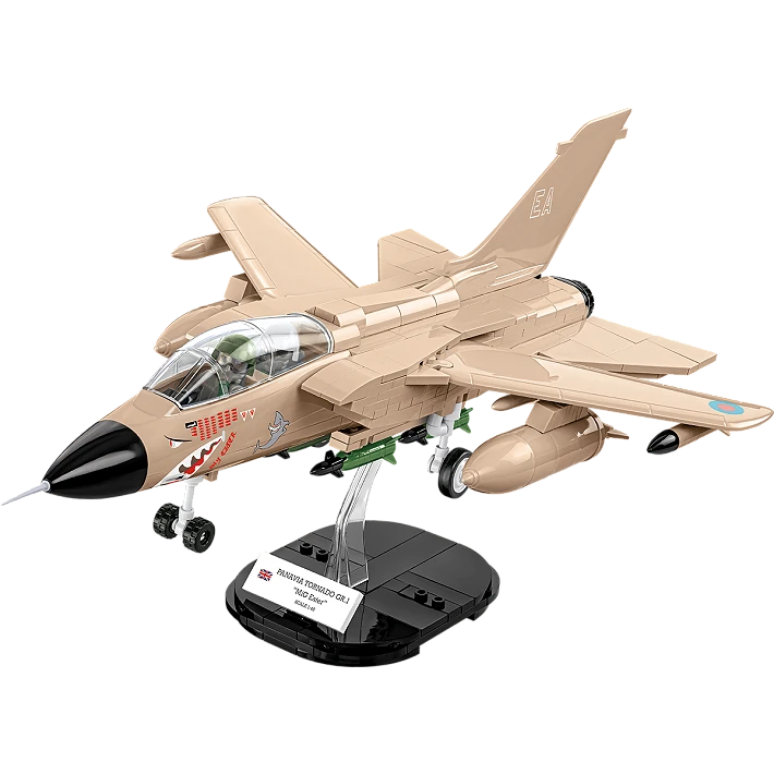 A photo of the assembled model plane, stood on its black display stand. The jet consists of various brown and black blocks, features a black nose cone, transparent cockpit wind shield. and has several brown and green bombs and missiles mounted beneath it. A small white plaque displaying the aircraft’s name and country of origin sits on the display stand. 