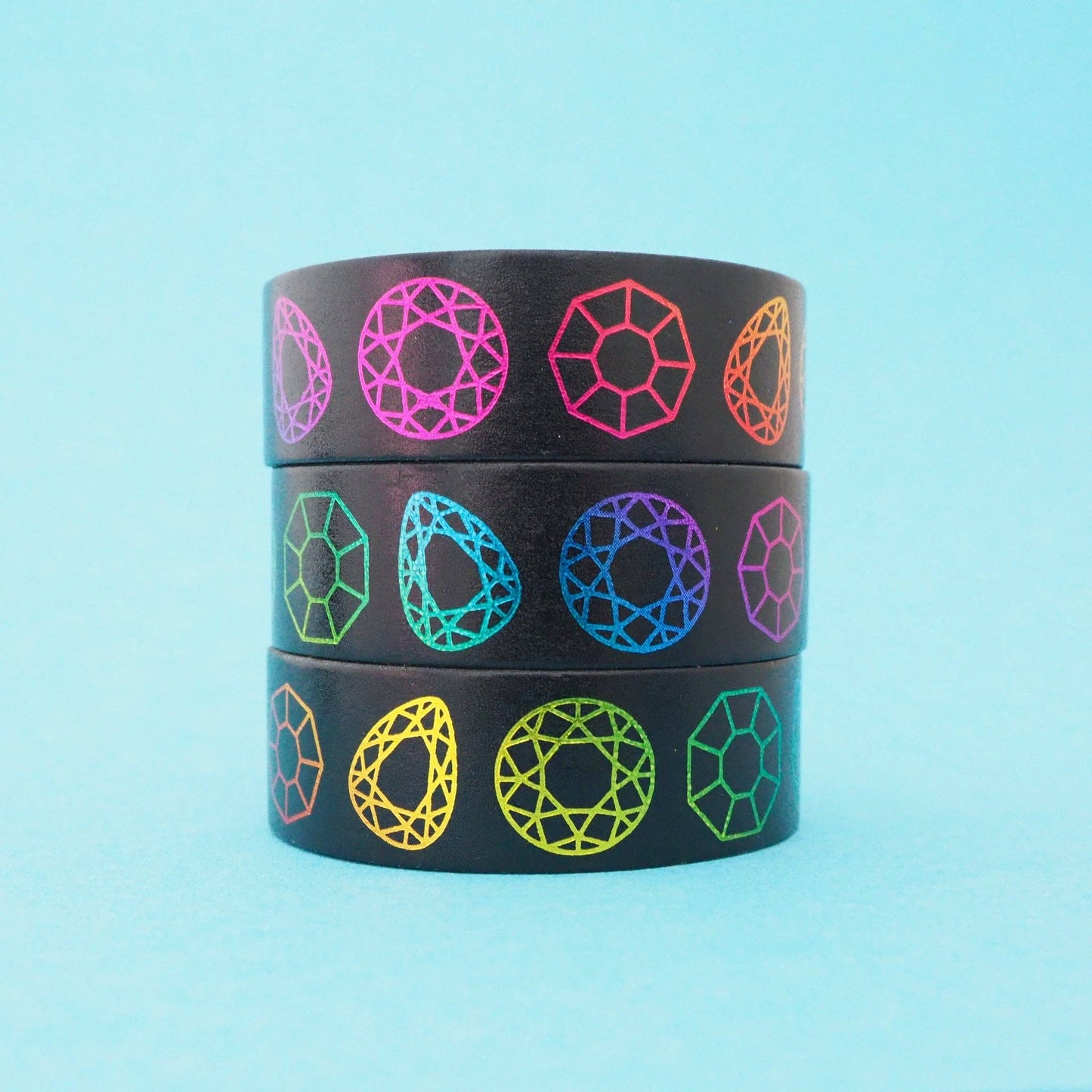 3 rolls of washi tape, black with patterns of rainbow coloured geometric gem shapes.