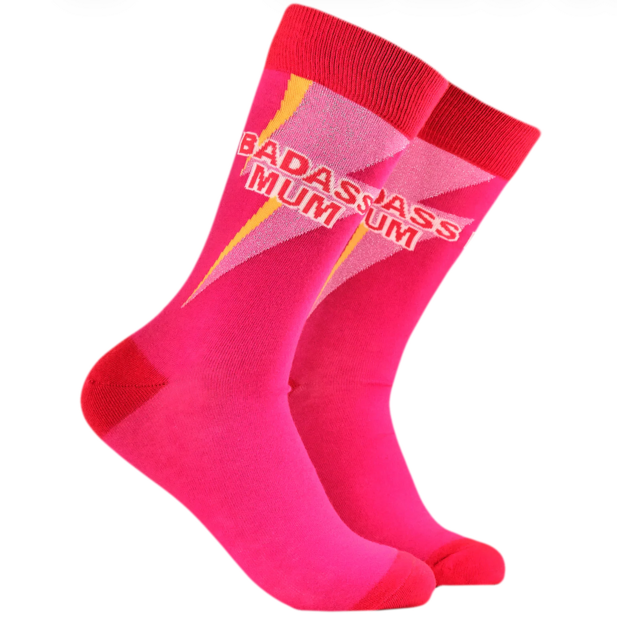 A pair of bright pink crew socks with a red cuff and toe, featuring the text 'BADASS MUM' in white outlined letters over a diagonal pink and yellow graphic, set against a plain white background.