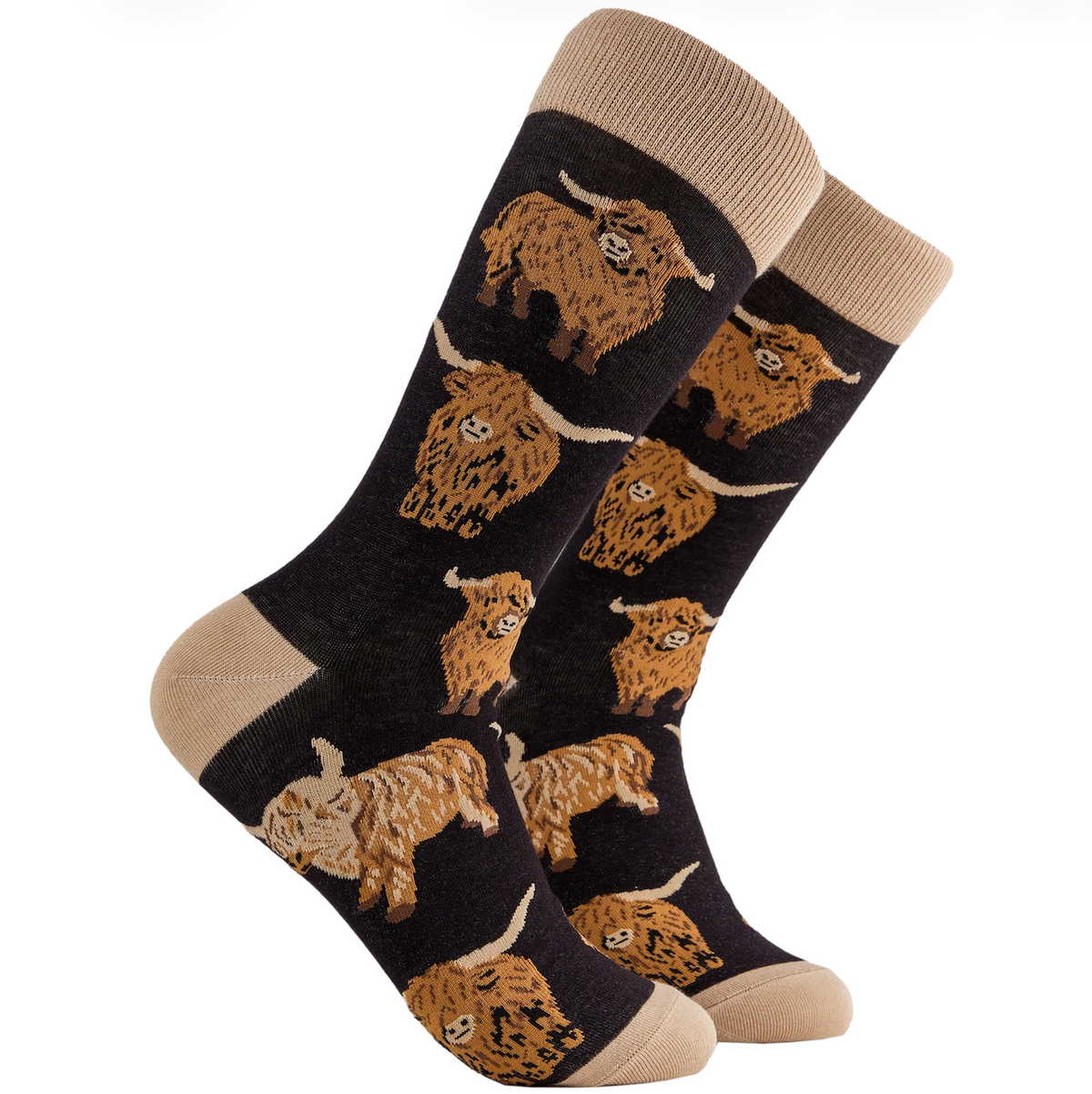 A pair of crew socks with a dark charcoal/black background featuring a repeating pattern of tan and brown Highland cows, finished with beige heels, toes, and cuffs.