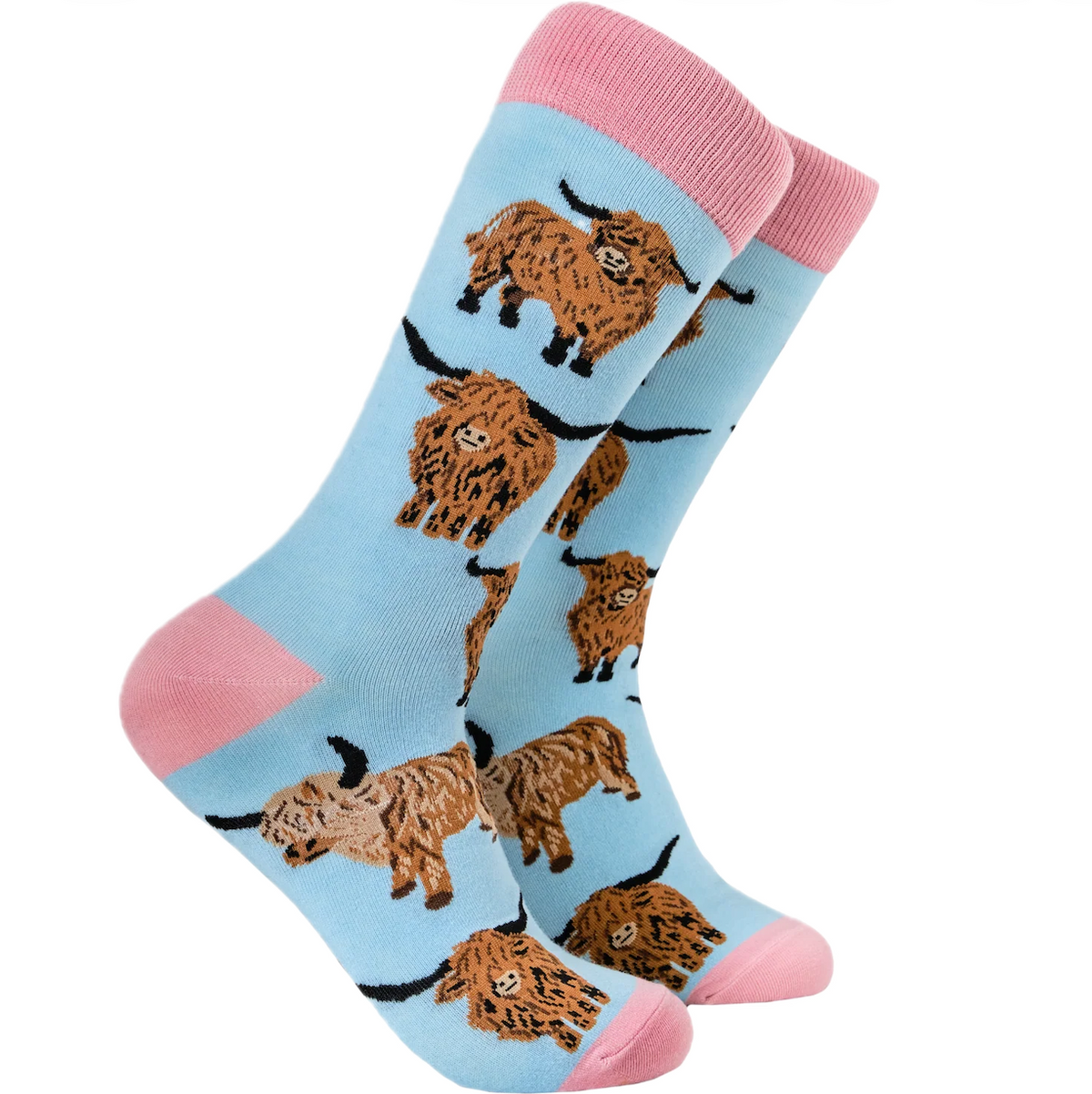 A pair of light blue crew socks with pink heels, toes, and cuffs, featuring an all-over pattern of brown highland cows with black horns, shown on a plain white background.