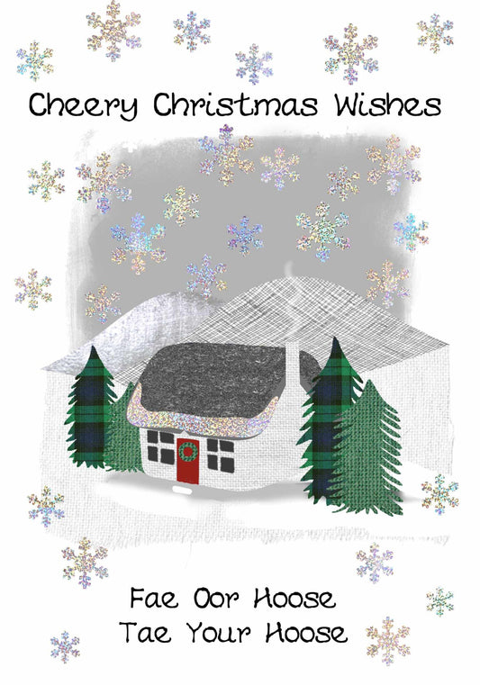 A festive Christmas greeting card design with the text 'Cheery Christmas Wishes' at the top and 'Fae Oor Hoose / Tae Your Hoose' at the bottom. The artwork shows a small white house with a dark roof, green trees, and many iridescent snowflakes falling on a white background.