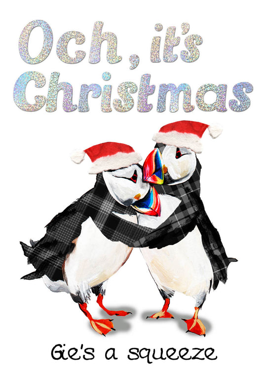 A festive Christmas illustration featuring two puffins hugging and wearing Santa hats, with the text 'Och, it's Christmas' at the top and 'Gie's a squeeze' at the bottom on a white background.