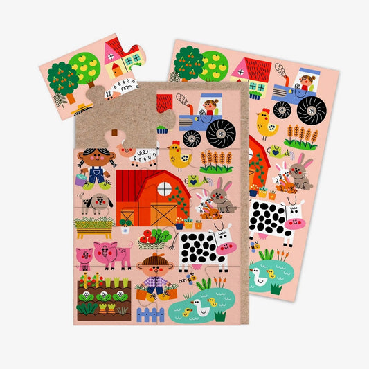 A jigsaw greeting card featuring colourful illustration of a farm yard on a pale pink background, with a brown kraft paper envelope visible on the left side, on a clean white background.