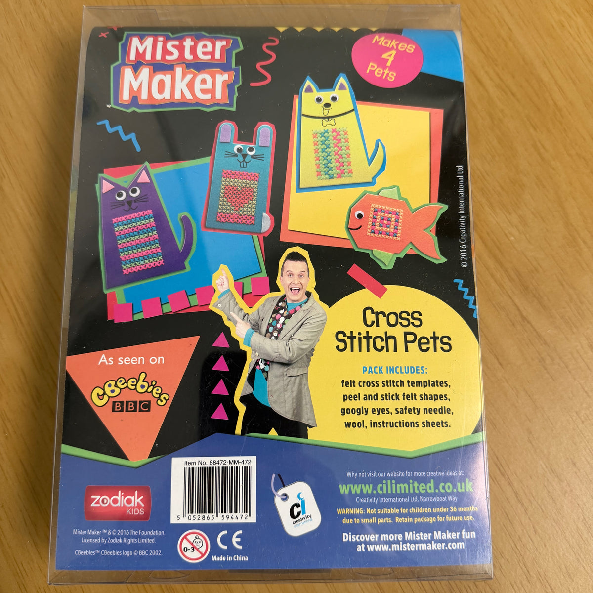 Reverse of the packaging, featuring colourful cartoon pet designs and a picture of Mister Maker. The package is shown in its plastic box on a wooden tabletop.