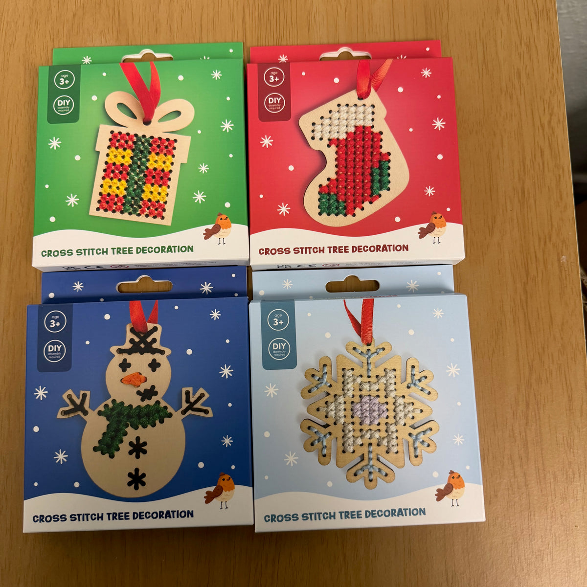 A picture showing all four variants of the cross stitch tree decoration, a present, a stocking, a snowman and a snowflake.
