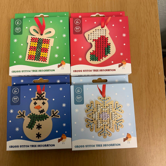 A picture showing all four variants of the cross stitch tree decoration, a present, a stocking, a snowman and a snowflake.