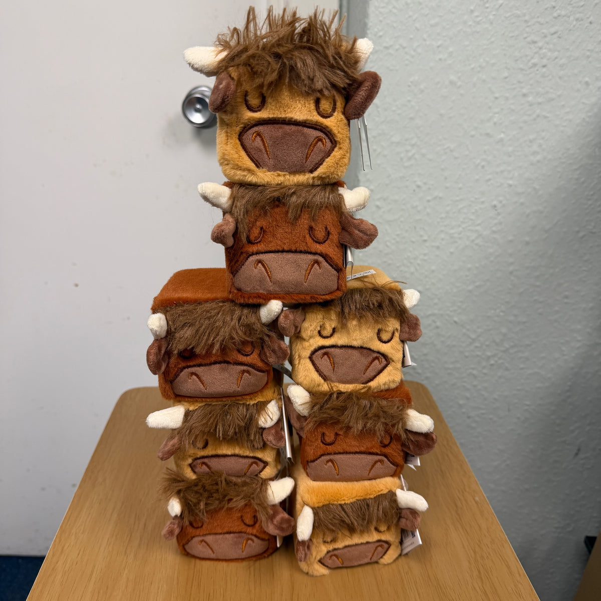 8 of the Highland Cow plushie blox stacked on a wooden table.