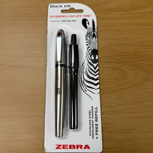 A white cardboard pack containing a stainless steel permanent marker, and black refill cartridge, both of which are displayed through clear plastic. An illustration of a zebra is printed on the right side of the card. 