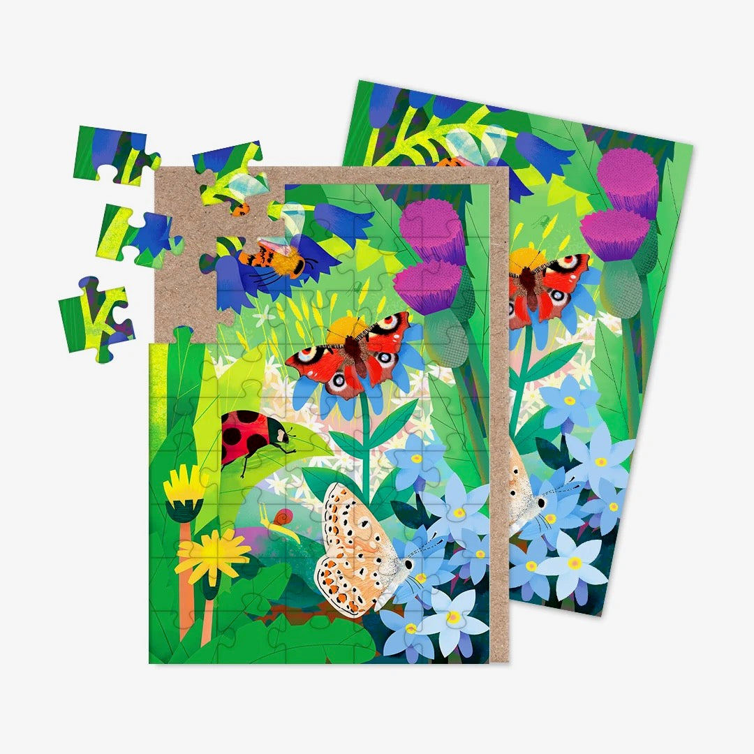 A jigsaw greeting card featuring illustrations of UK birds, including a butterfly, bee, ladybird and moth with a background in shades of green, blue and purple with a brown kraft paper envelope visible on the left side, on a clean white background.