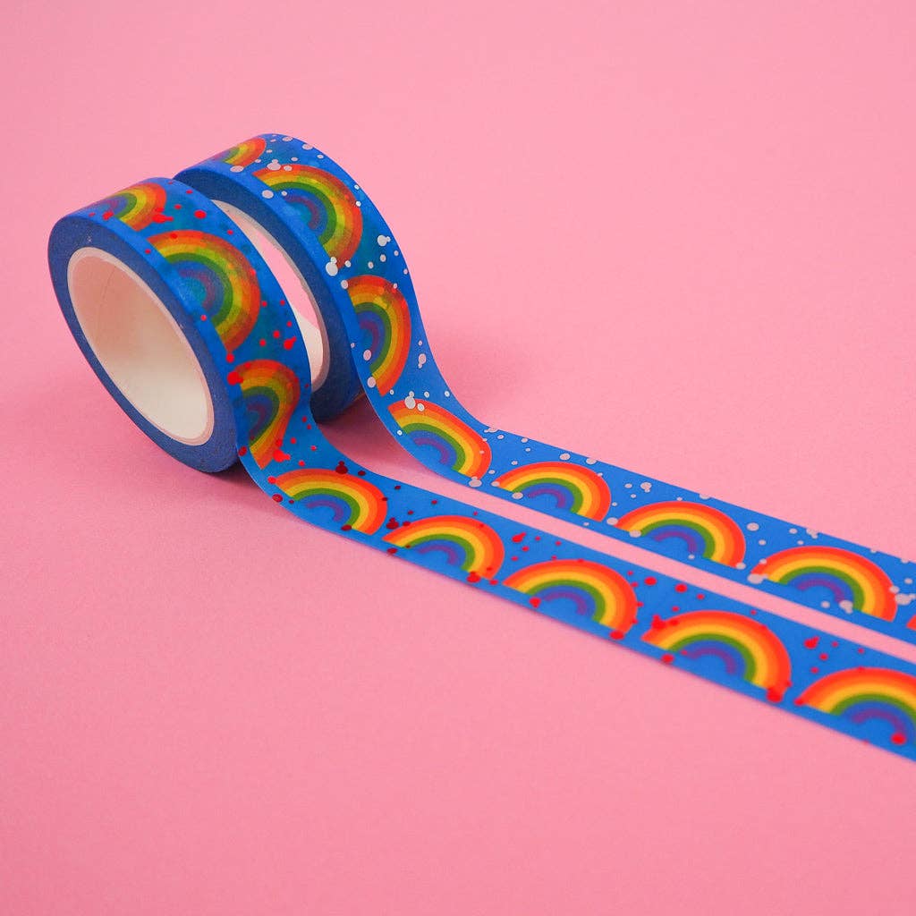 Two rolls of washi tape, partially unrolled, blue with a repeated pattern of rainbows, one with pale blue dots the other with red dots