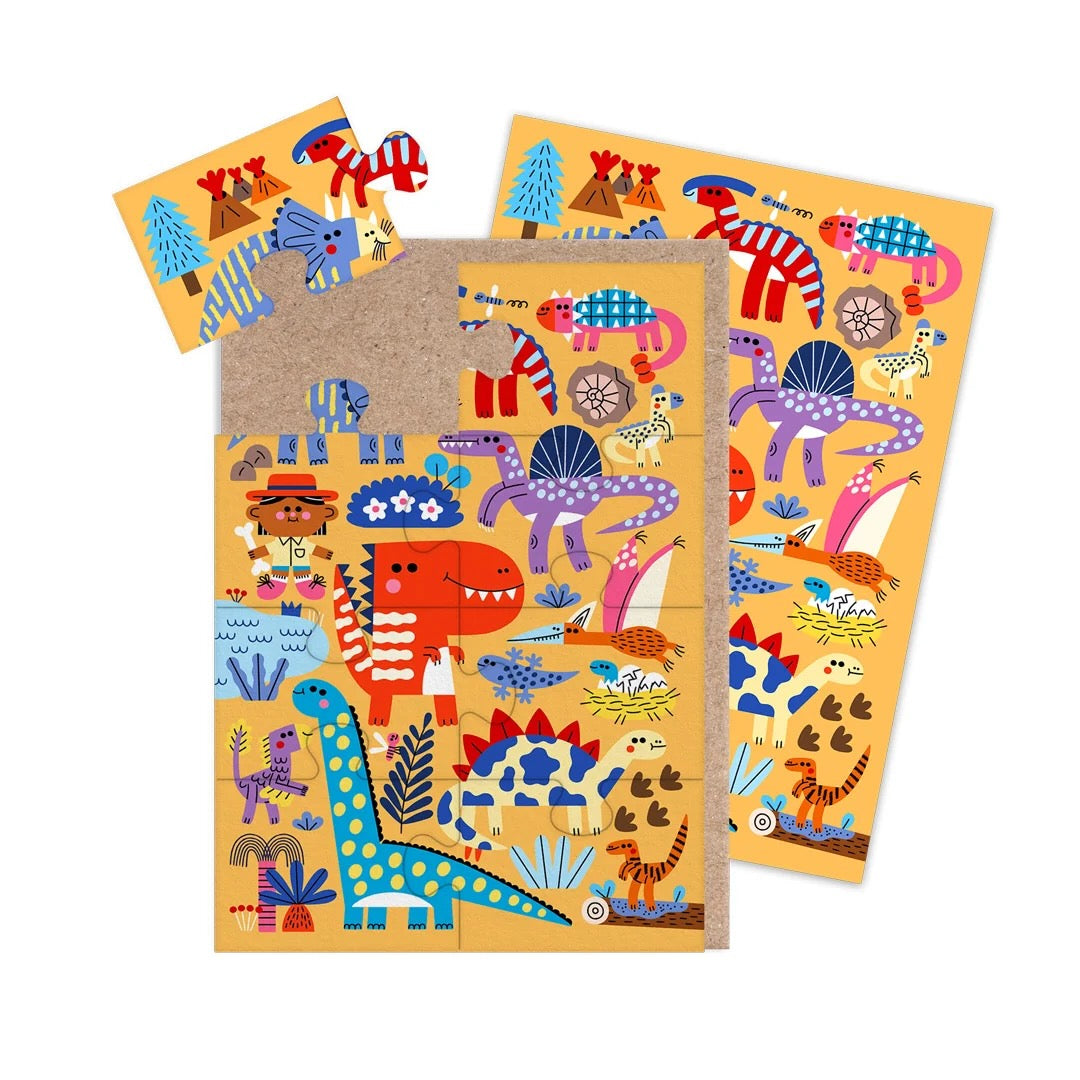 A jigsaw greeting card featuring colourful dinosaur illustrations on a yellow-orange background, with a brown kraft paper envelope visible on the left side, on a clean white background.